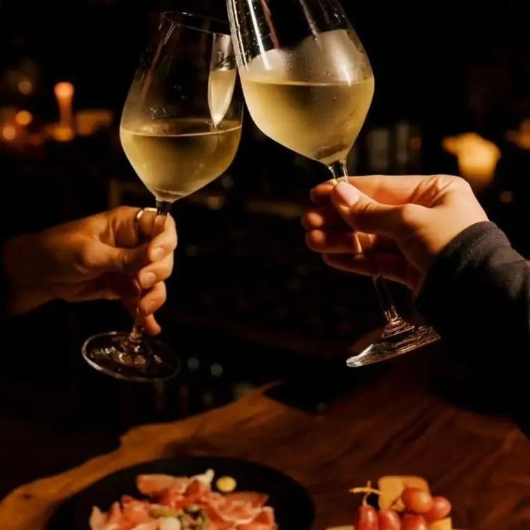 Dos copas de vino blanco brindando a la luz de las velas.