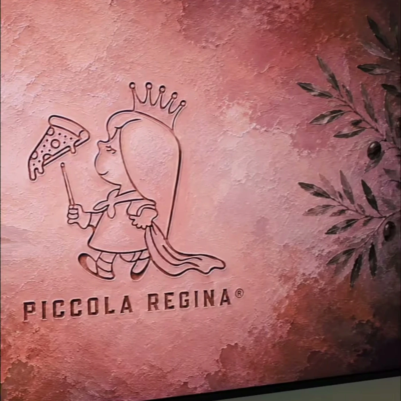 Relieve de la pequeña reina de Piccola Regina sobre estuco terracota, con ramas de olivo pintadas al lado.